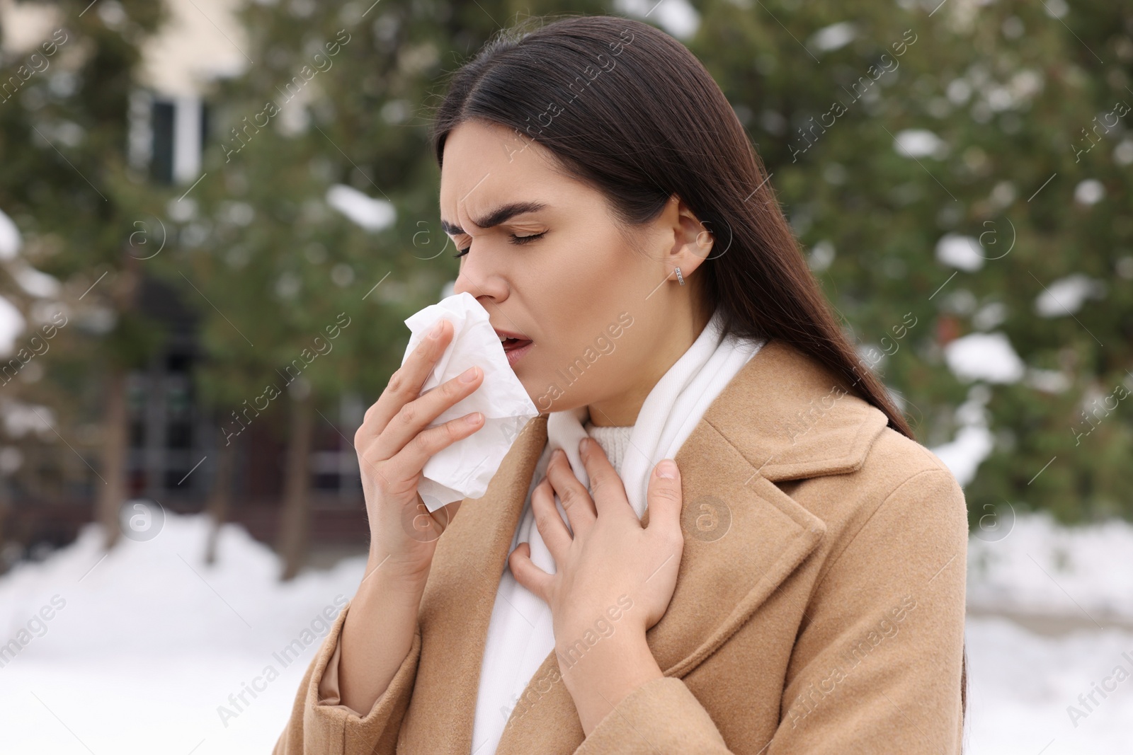 Photo of Woman in coat coughing outdoors. Cold symptoms