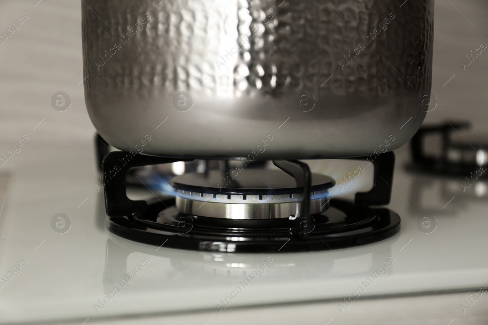 Photo of Shiny steel saucepan on modern gas stove, closeup