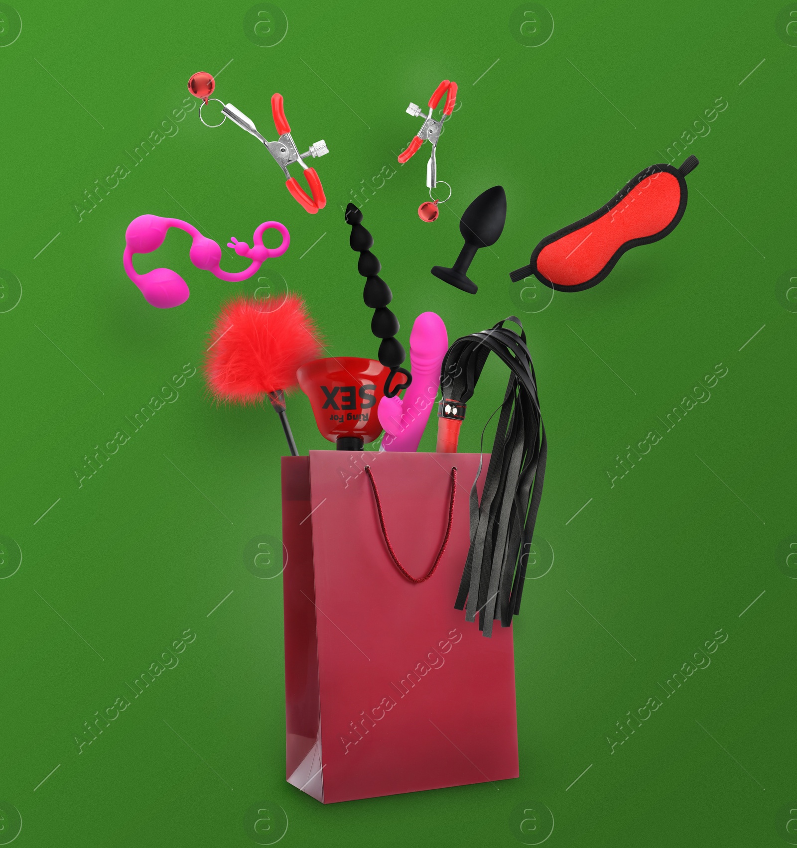 Image of DIfferent sex toys and accessories falling into paper shopping bag on green background