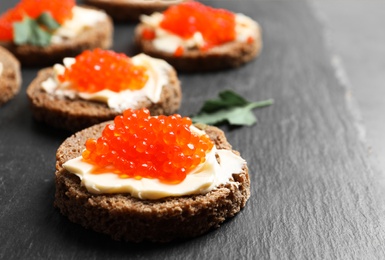 Photo of Delicious sandwiches with red caviar on slate plate