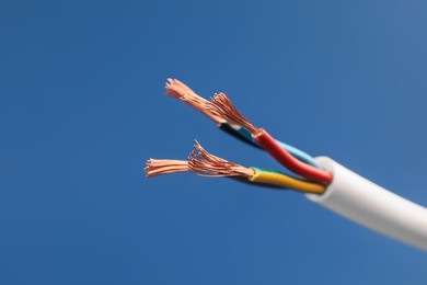 Photo of Cable with stripped wires on blue background, closeup
