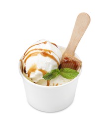 Photo of Tasty ice cream with caramel sauce, mint leaves and candy in paper cup isolated on white