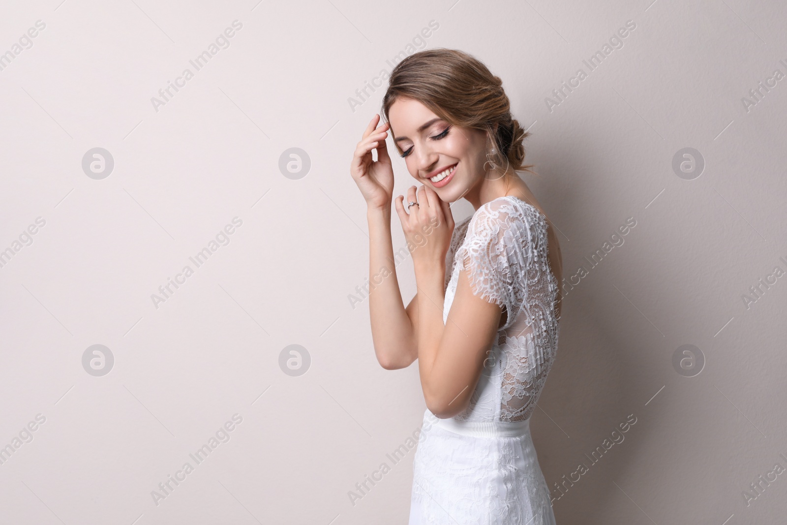 Photo of Young bride with elegant wedding hairstyle on beige background. Space for text