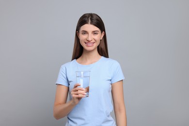Photo of Healthy habit. Portrait of happy woman holding glass with fresh water on grey background