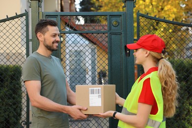 Photo of Man receiving parcel from courier in uniform outdoors