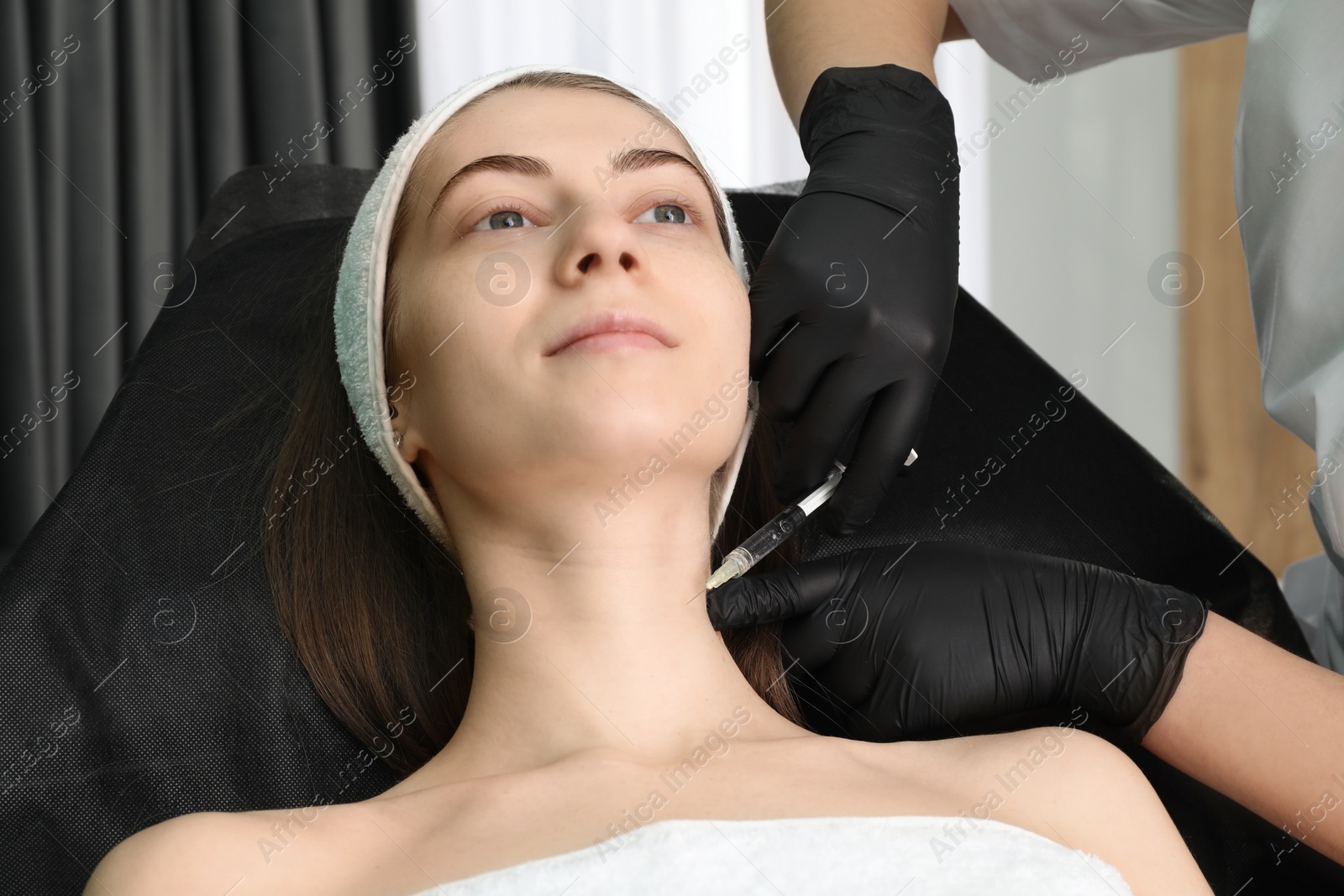 Photo of Cosmetologist giving neck injection to patient in clinic, closeup. Cosmetic surgery