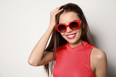 Photo of Beautiful woman in stylish sunglasses on light background