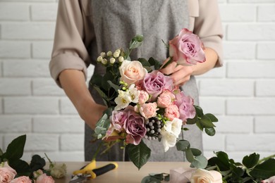 Photo of Florist creating beautiful bouquet at table indoors, closeup
