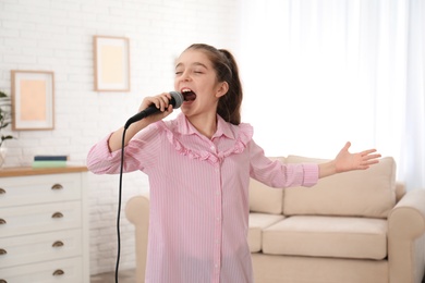 Cute girl singing in microphone at home