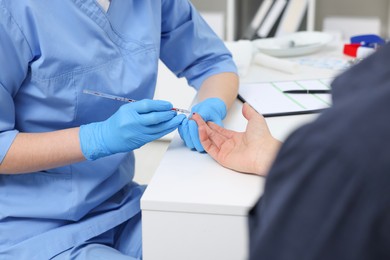 Photo of Laboratory testing. Doctor taking blood sample from patient at white table in hospital, closeup