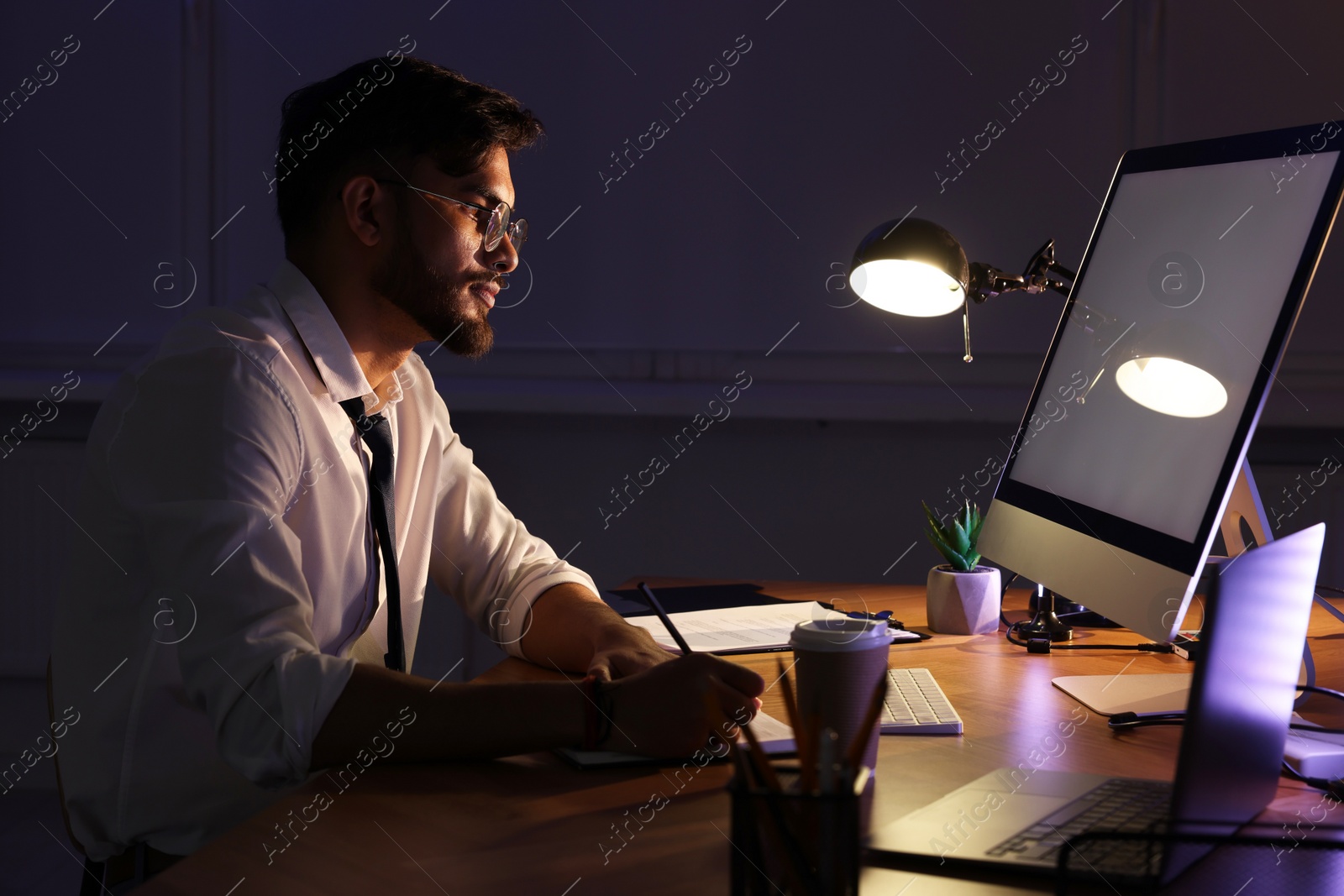 Photo of Tired young man working late in office