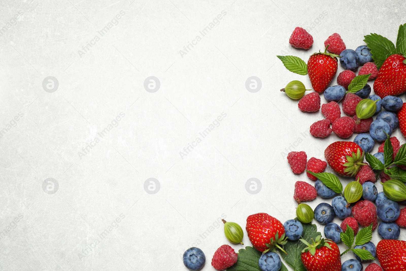 Photo of Mix of fresh berries on light table, flat lay. Space for text