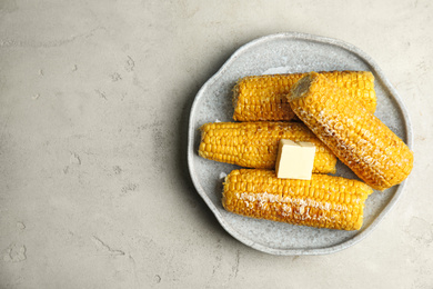 Photo of Delicious grilled corn with butter on light grey table, top view. Space for text