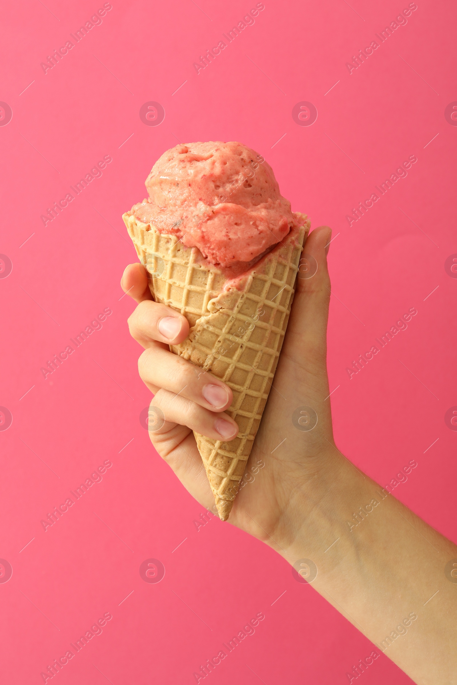 Photo of Woman holding waffle cone with delicious ice cream on pink background, closeup