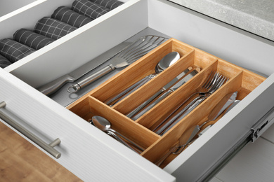 Photo of Open drawer with different utensils and folded towels. Order in kitchen