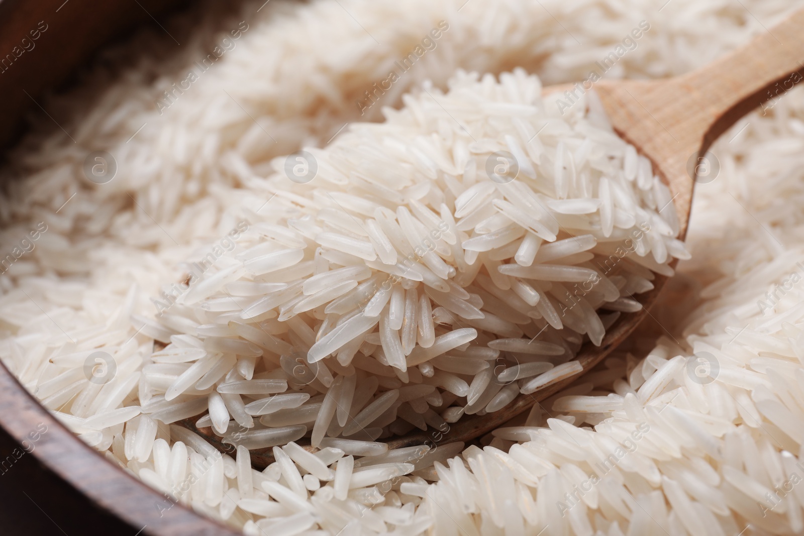 Photo of Raw basmati rice in bowl and spoon, closeup