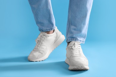 Photo of Man walking in stylish sneakers on light blue background, closeup