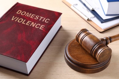 Photo of Law book and gavel on wooden table. Protection from domestic violence