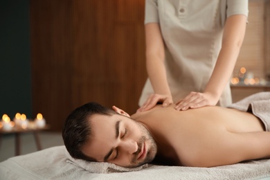 Handsome man receiving back massage in spa salon