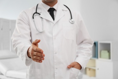 Photo of Male doctor offering handshake in clinic, closeup