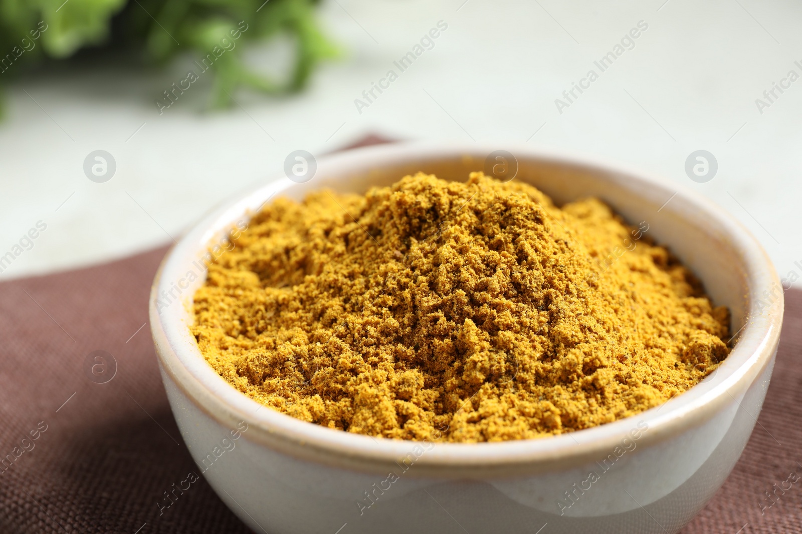 Photo of Curry powder in bowl on white table, closeup