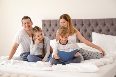 Photo of Child reading book to family in bedroom. Spending time together