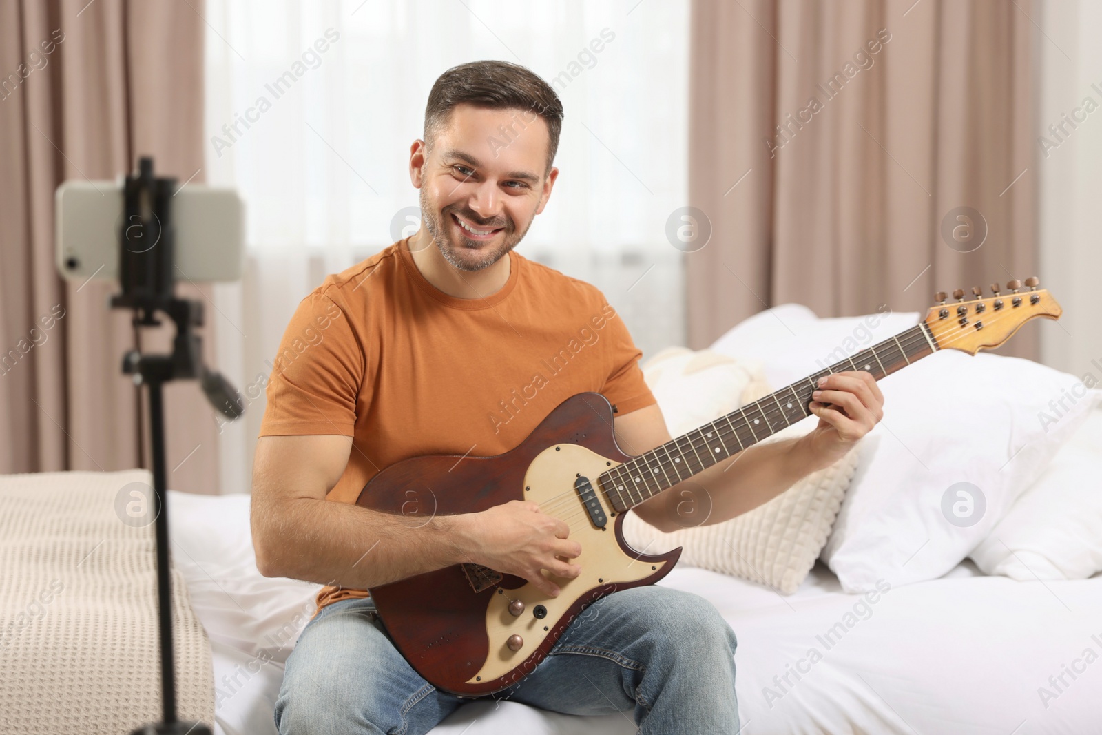 Photo of Music teacher with guitar conducting online lesson at home. Time for hobby