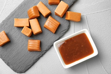 Delicious candies and caramel sauce on table, top view