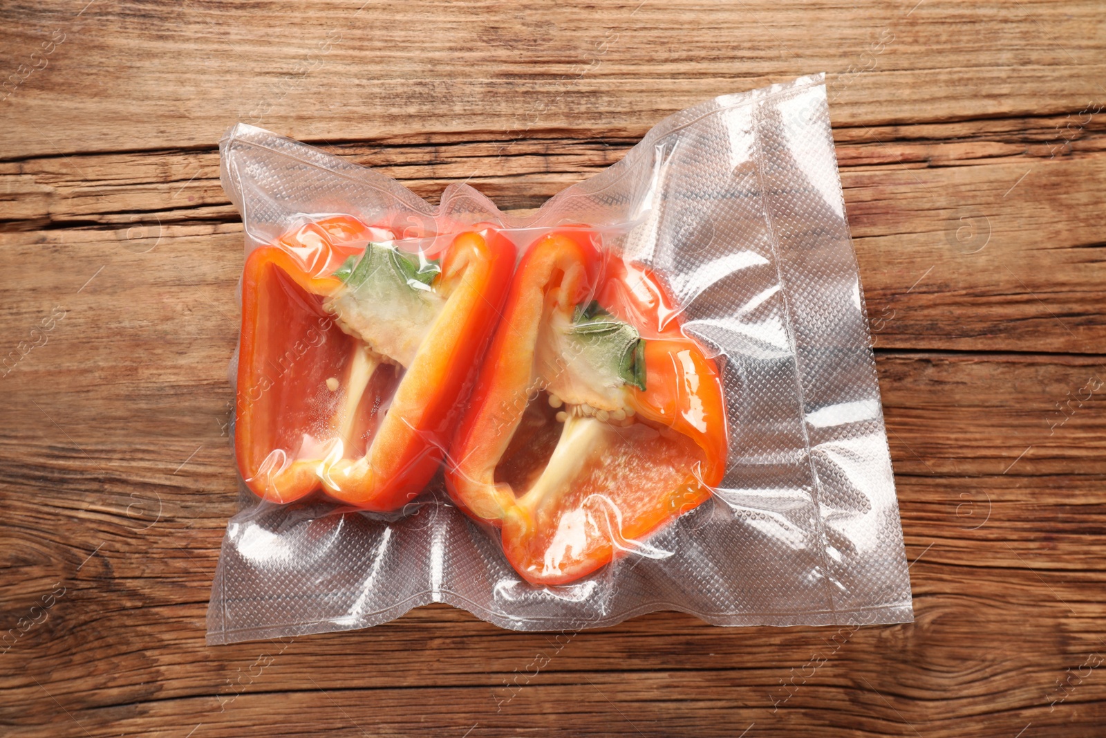 Photo of Vacuum pack of bell pepper on wooden table, top view