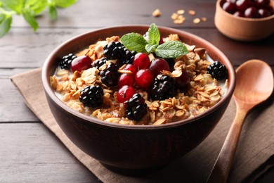 Photo of Bowl of muesli served with berries and milk on wooden table, closeup
