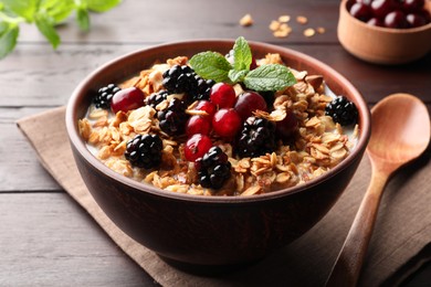 Bowl of muesli served with berries and milk on wooden table, closeup