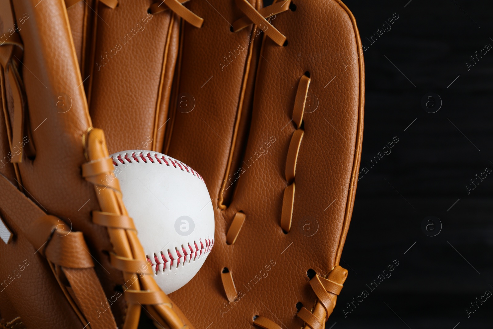 Photo of Catcher's mitt and baseball ball on black background, closeup. Sports game