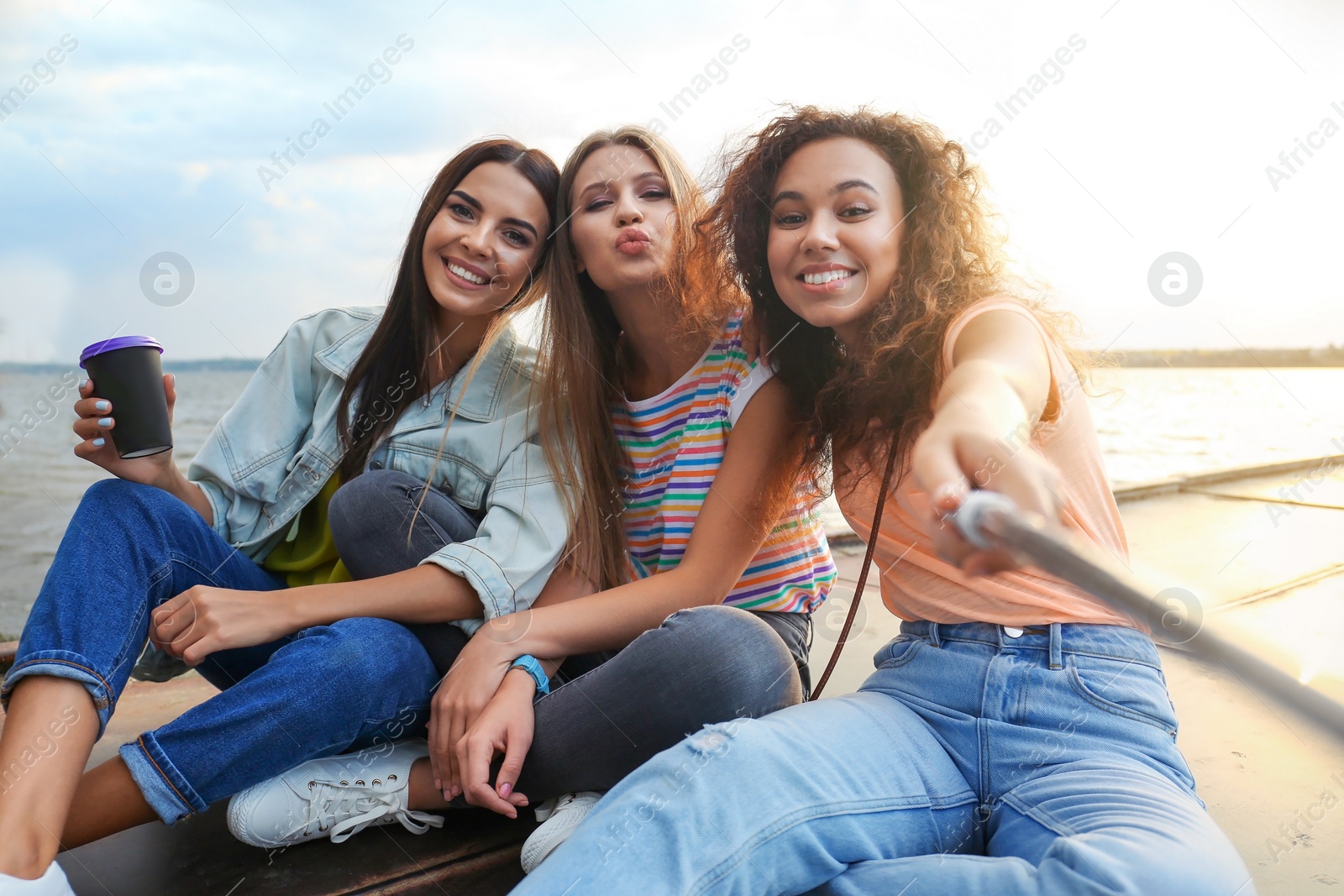 Photo of Happy young women taking selfie outdoors on sunny day