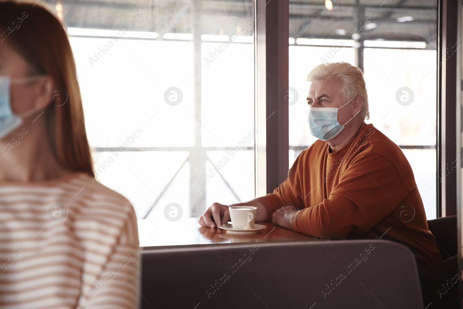 Photo of Senior man with medical mask in cafe. Virus protection