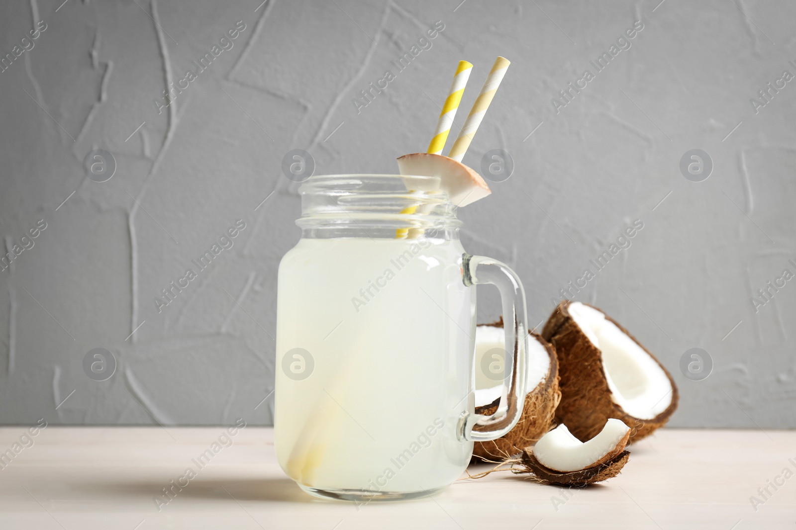 Photo of Mason jar with coconut water and fresh nuts on table