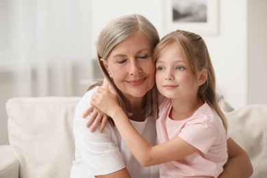 Photo of Happy grandmother hugging her granddaughter at home, space for text
