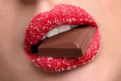 Closeup view of young woman with beautiful lips covered in sugar eating chocolate