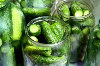 Photo of Many pickling jars with fresh cucumbers, closeup