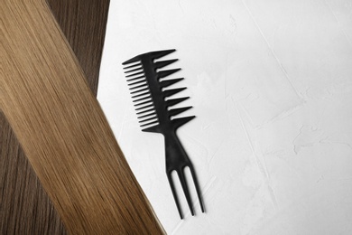 Beautiful straight brown hair and comb on light background, flat lay. Space for text