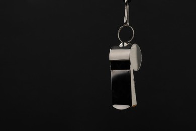 Photo of Referee equipment. Metal whistle on black background, closeup and space for text