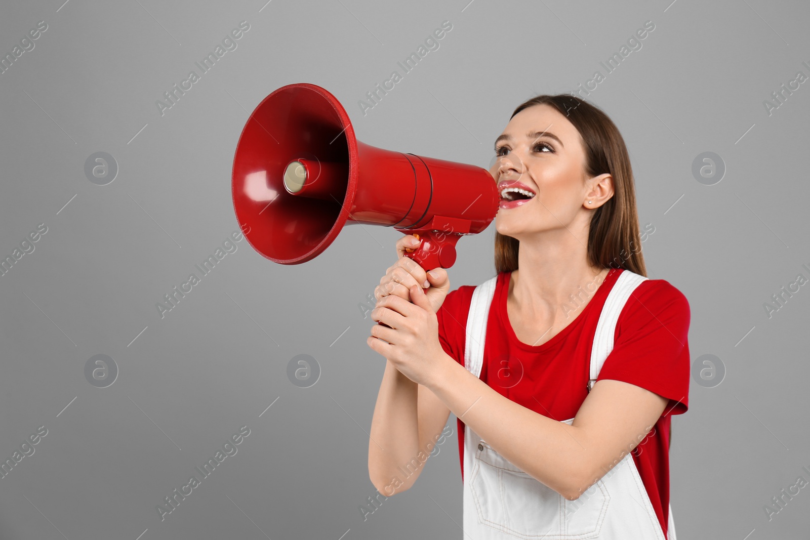 Photo of Young woman with megaphone on light grey background