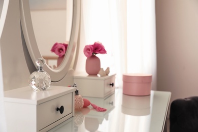 White dressing table with decor and bottles of perfumes in room