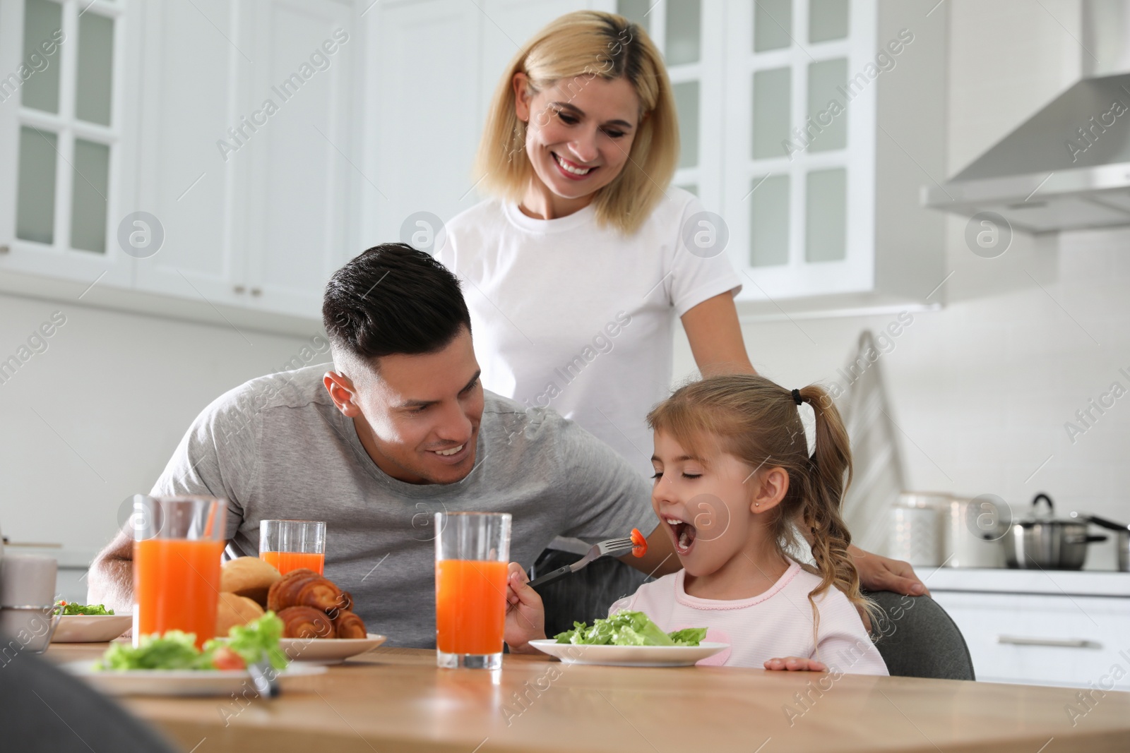 Photo of Happy family having breakfast together at table in modern kitchen