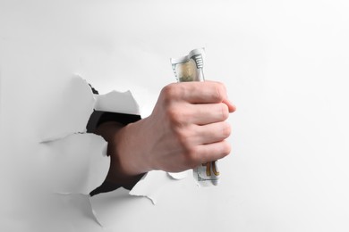 Photo of Man breaking through white paper with money in fist, closeup