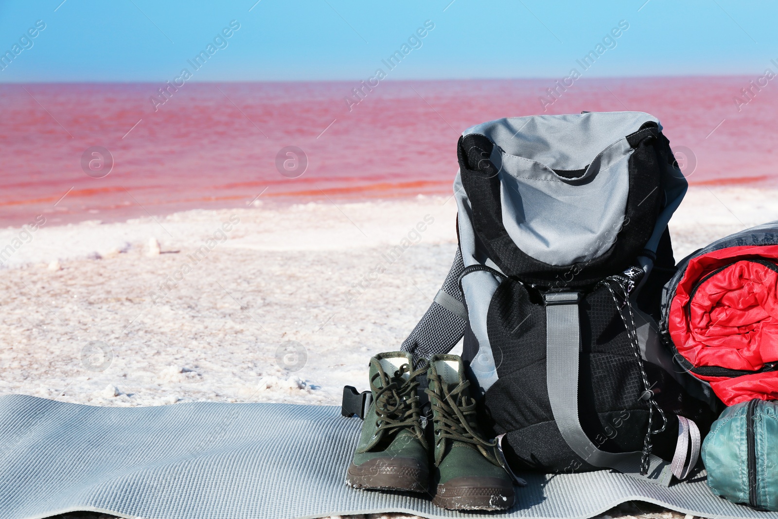 Photo of Set of camping equipment with sleeping bag on coast of pink lake