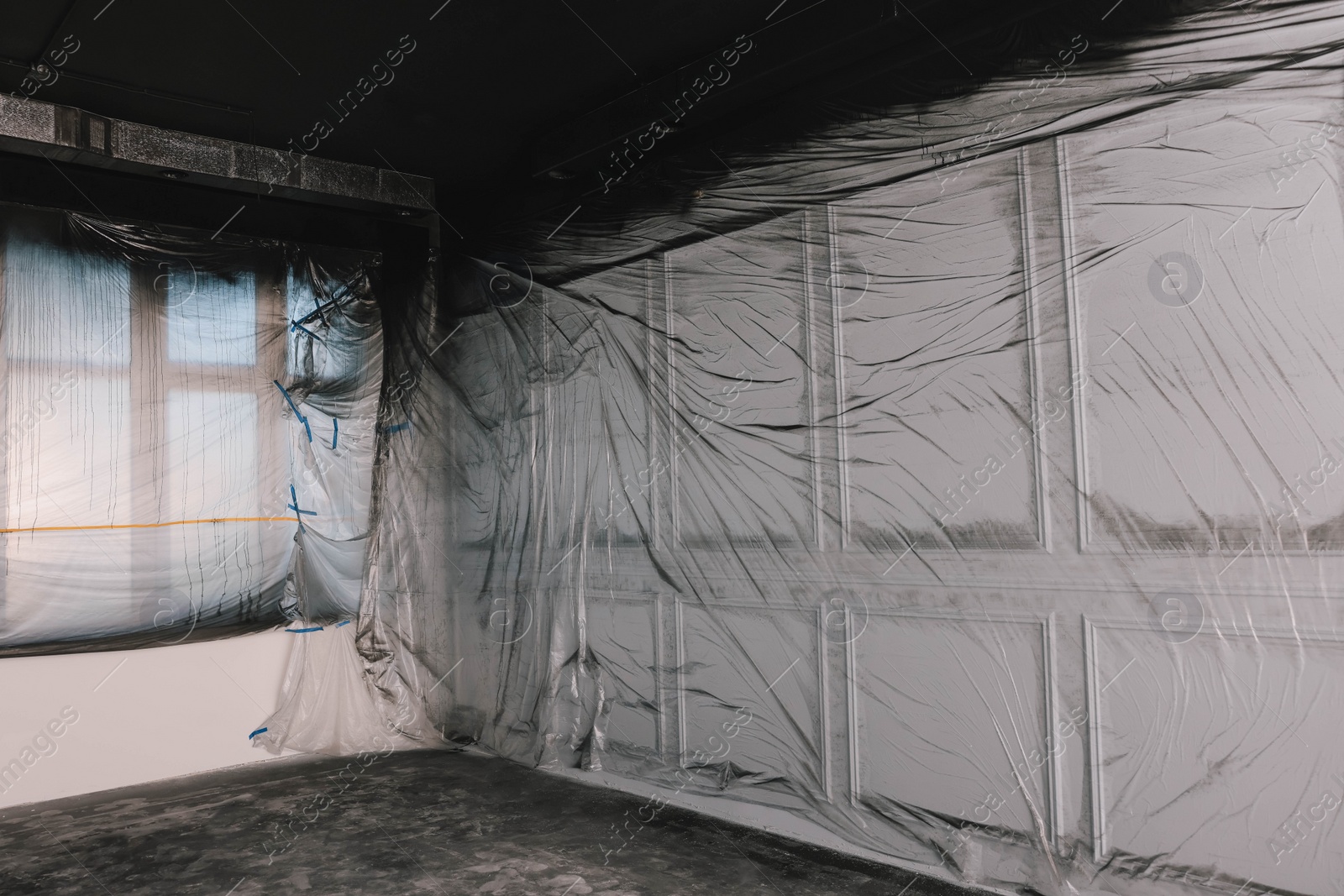 Photo of Windows and wall covered with plastic film in empty room