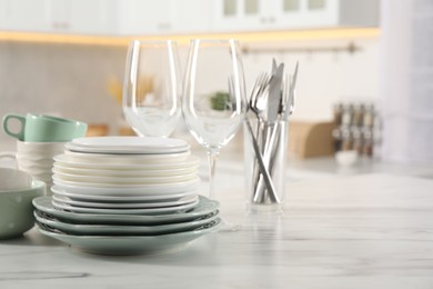 Photo of Many different clean dishware and glasses on white marble table in kitchen. Space for text