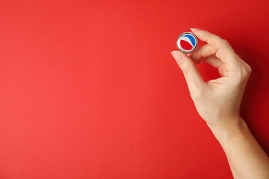 MYKOLAIV, UKRAINE - FEBRUARY 12, 2021: Woman holding Pepsi lid on red background, top view. Space for text