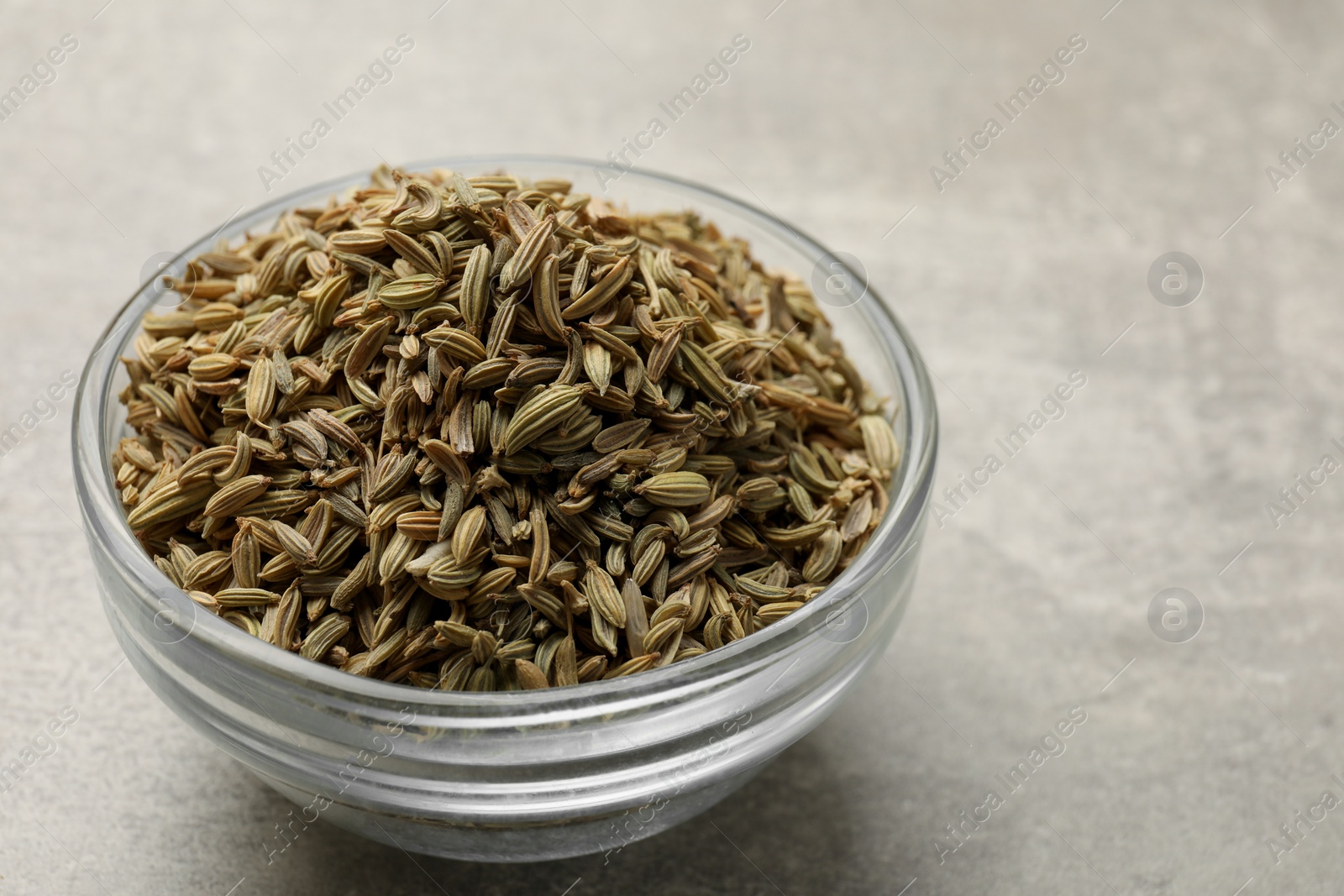 Photo of Fennel seeds in bowl on grey table, closeup. Space for text