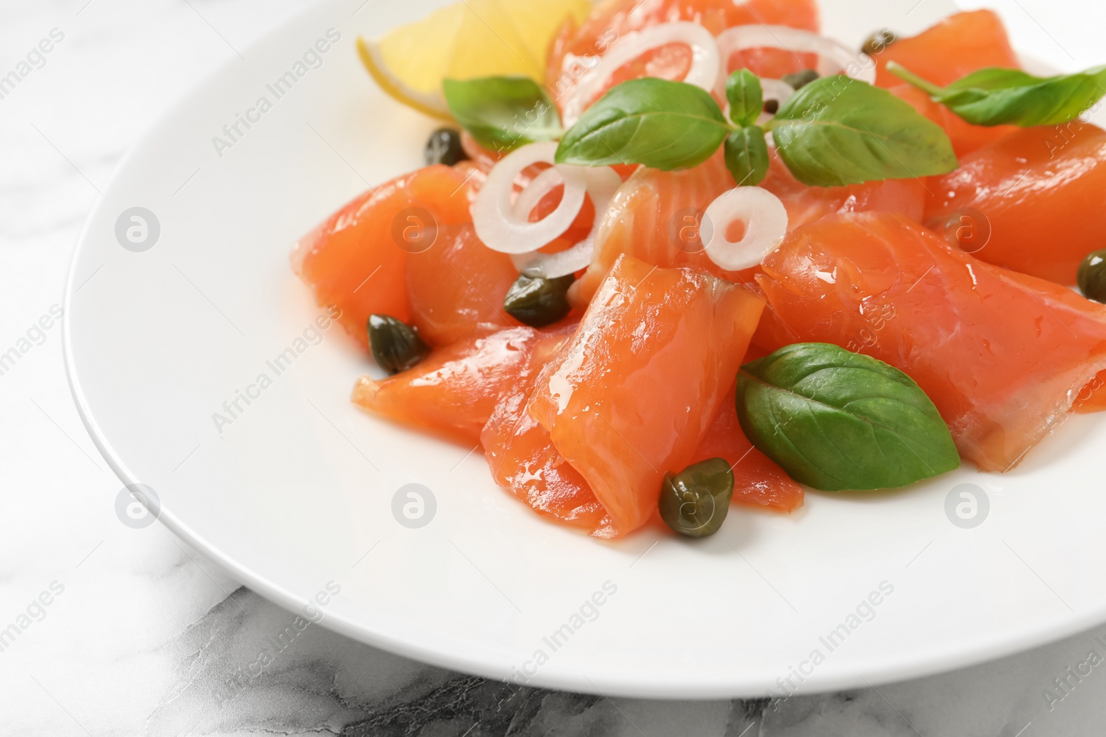 Photo of Delicious salmon carpaccio served on white marble table, closeup